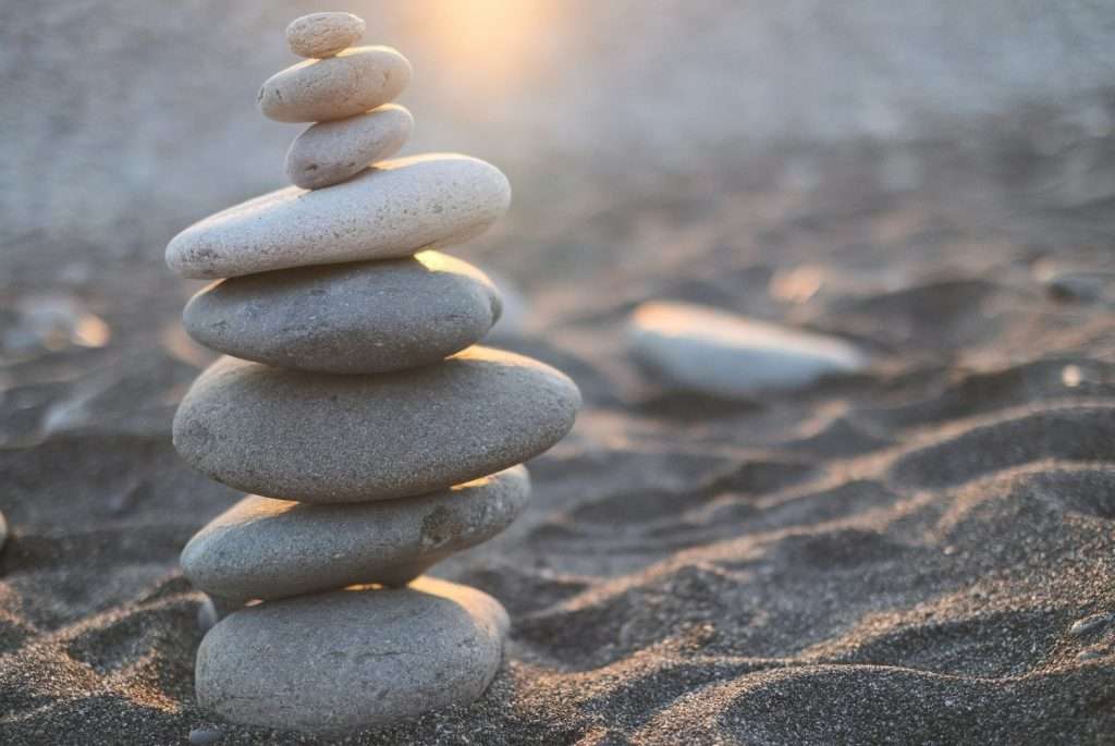 Torre di pietre grigie illuminate dal sole su una spiaggia sabbiosa: mantenere l'equilibrio per combattere gli effetti dell Primavera