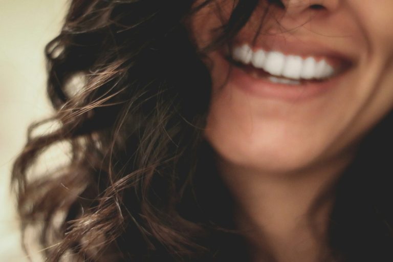 Avere una pelle radiosa: dettaglio di un viso di donna con lunghi capelli scuri mossi, un bel sorriso.